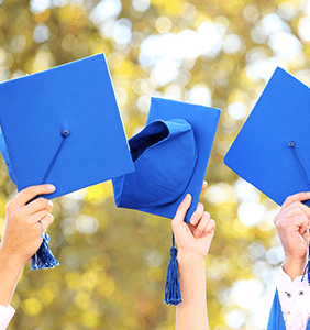 three blue graduation caps being held in the air