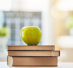 apple placed on top of books